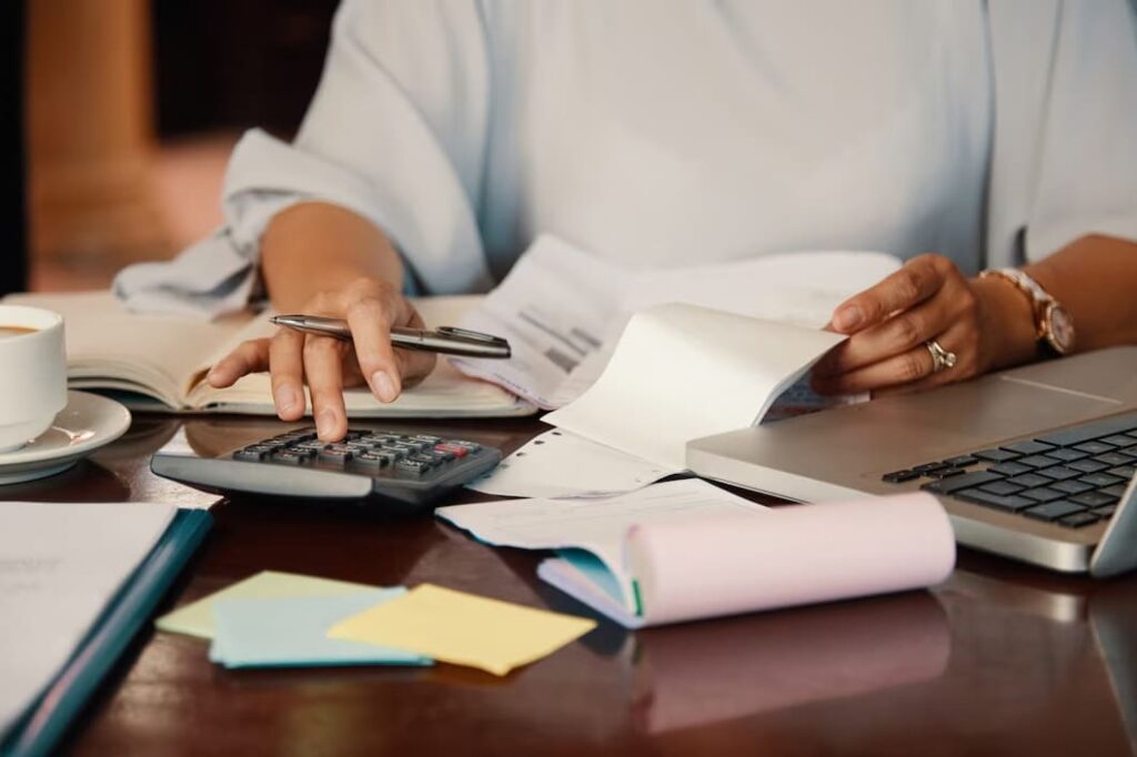 Mulher analisando papeis e números financeiros.